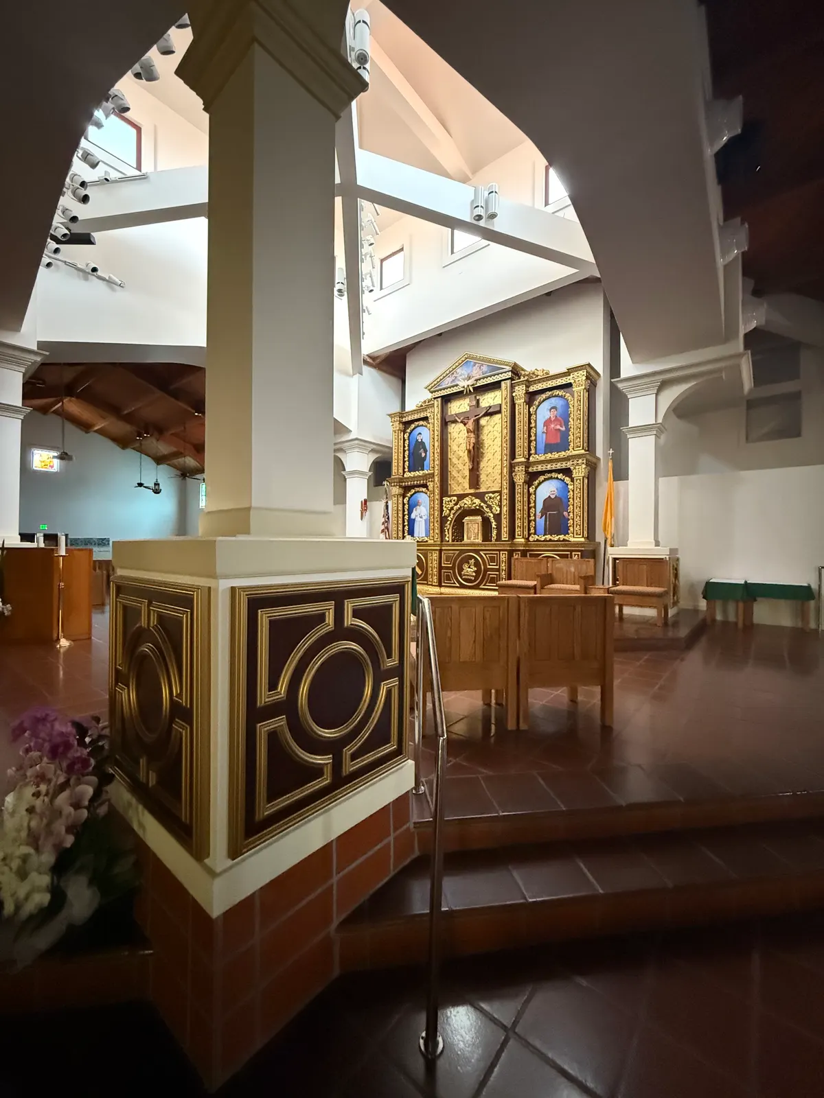 White column on a pedestal wrapped in dark and gold panels on two faces, at the edge of the raised sanctuary