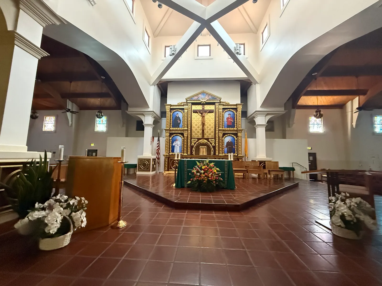 Blessed Sacrament's raised sanctuary seen from the nave, framed by white columns and arches under a beamed ceiling