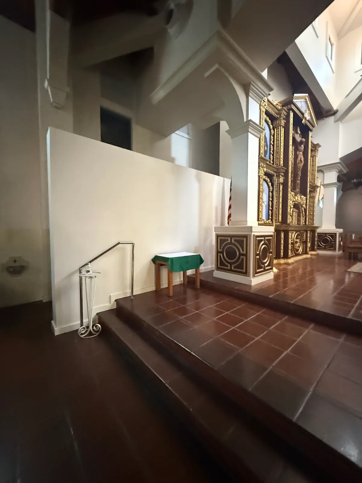 Paneled pedestals with gold-tone mouldings on either side of the altar platform, under white columns