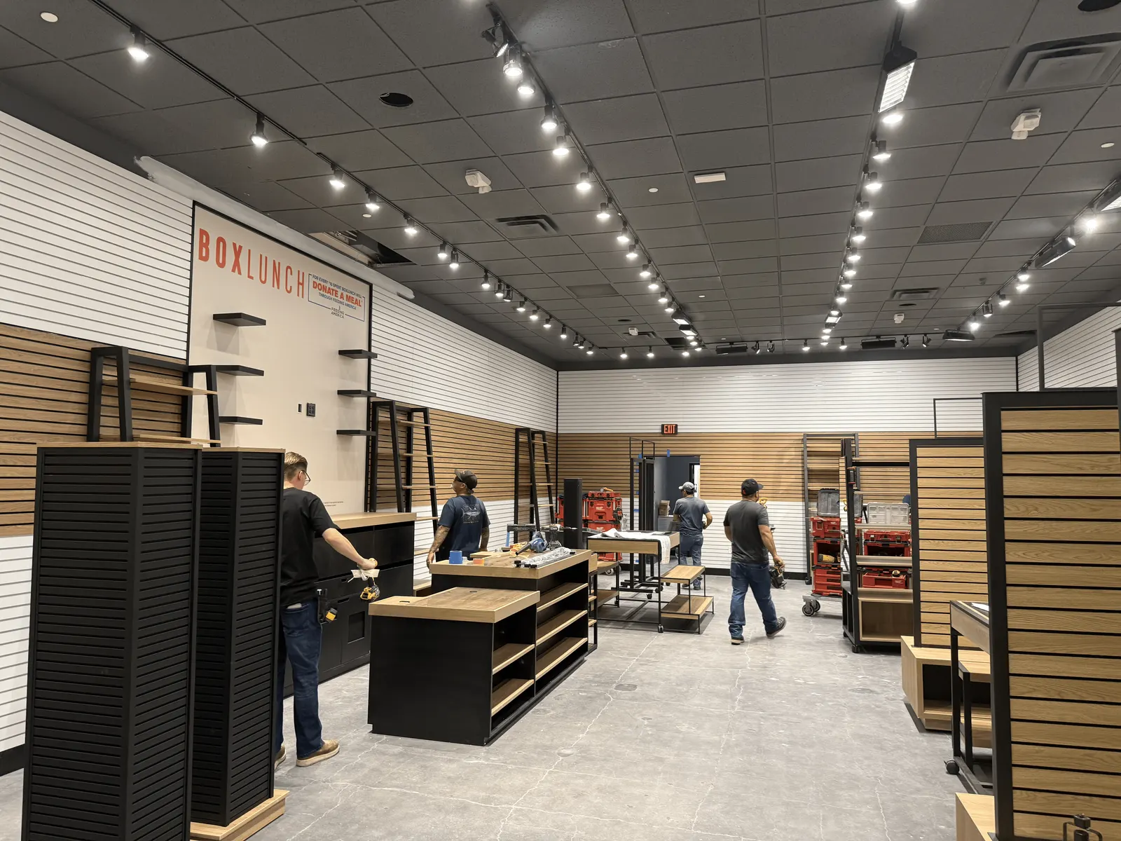 Crew installing owner-furnished retail fixtures inside the BoxLunch store in Ventura, mid-installation