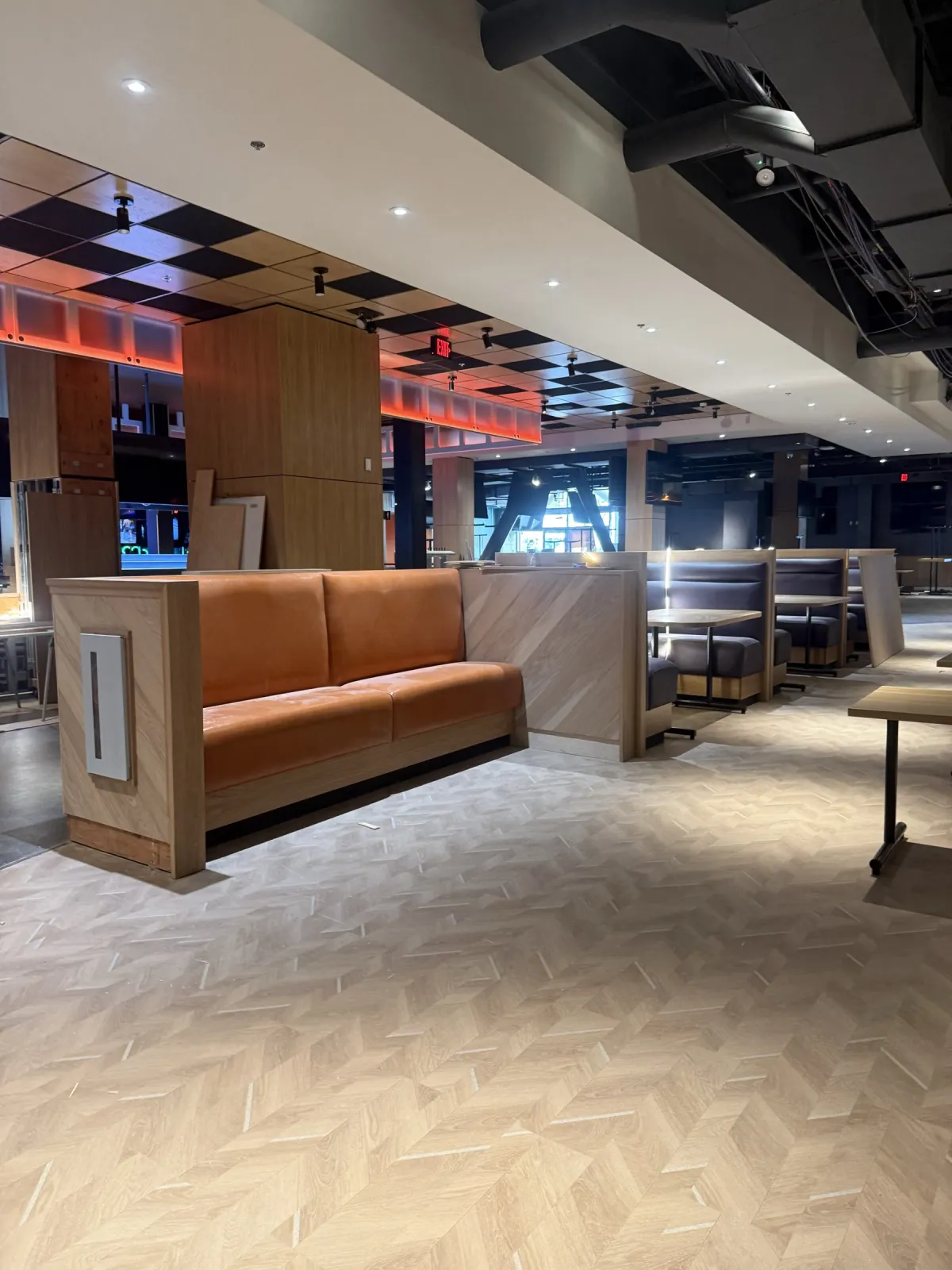 Orange upholstered booth in a light-wood surround beside a wood-clad column at Dave & Buster's Oakland