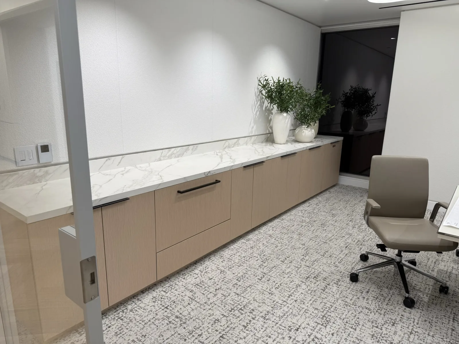 Low wood-grain credenza with a marble-look top and backsplash against a wall