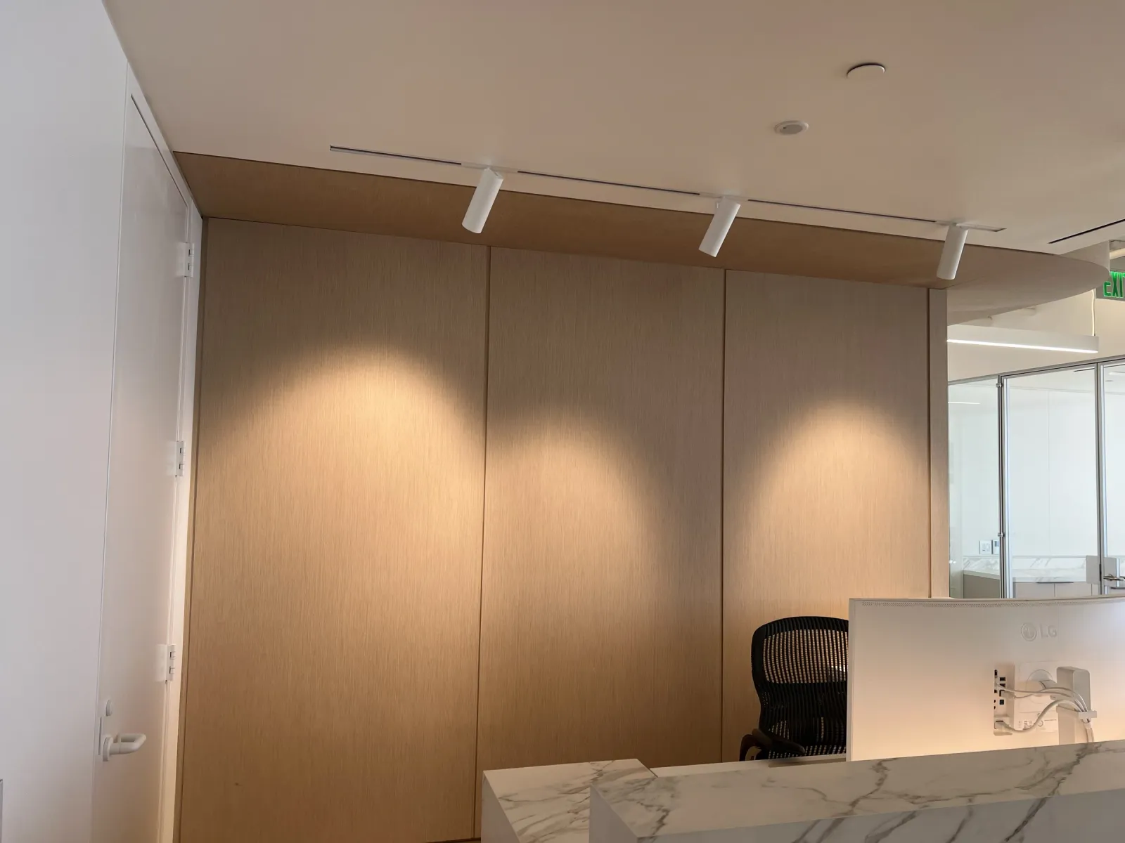 Three tall wood-grain wall panels under a matching soffit band behind the reception desk