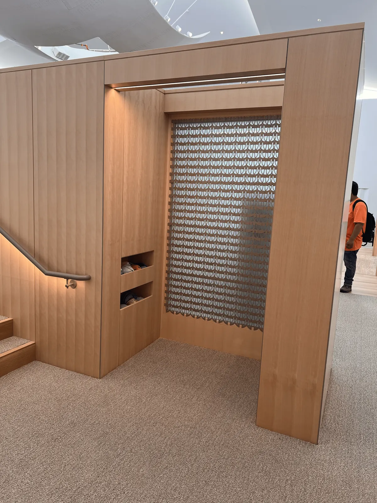Wood-paneled alcove with built-in storage niches and a patterned screen beside the sanctuary stair