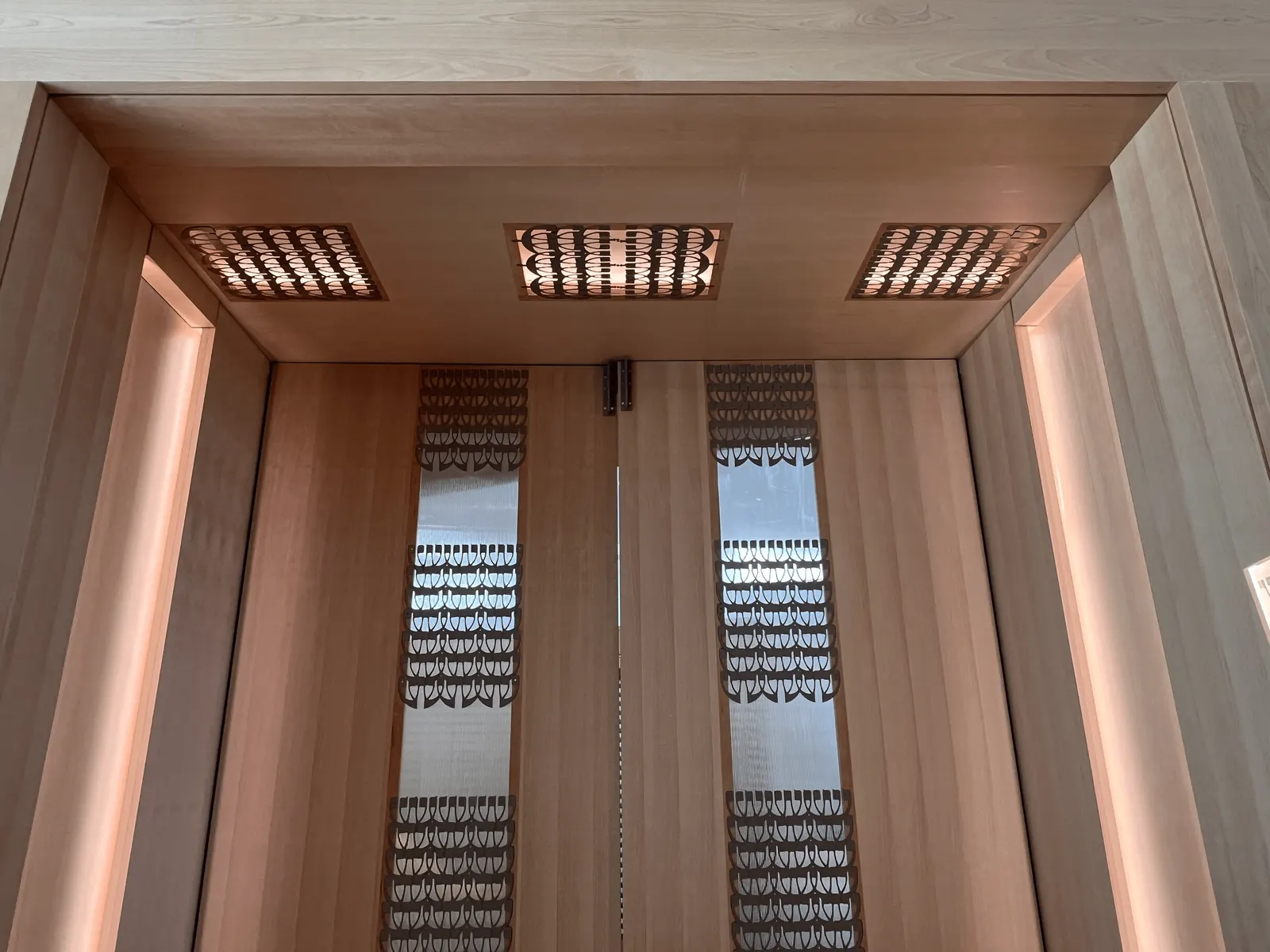 Wood pivot doors with patterned inserts and lit jambs at Kehillat Israel's sanctuary Portal