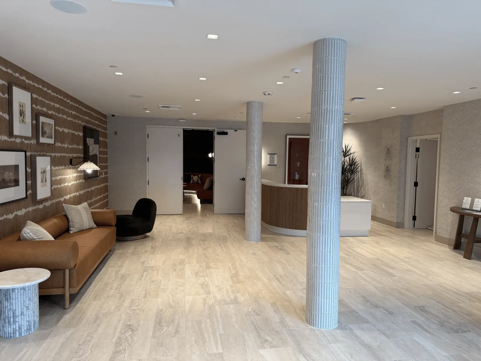Curved leasing reception desk with a vertical fluted wood front and white top in the Marlowe Sand Canyon lobby