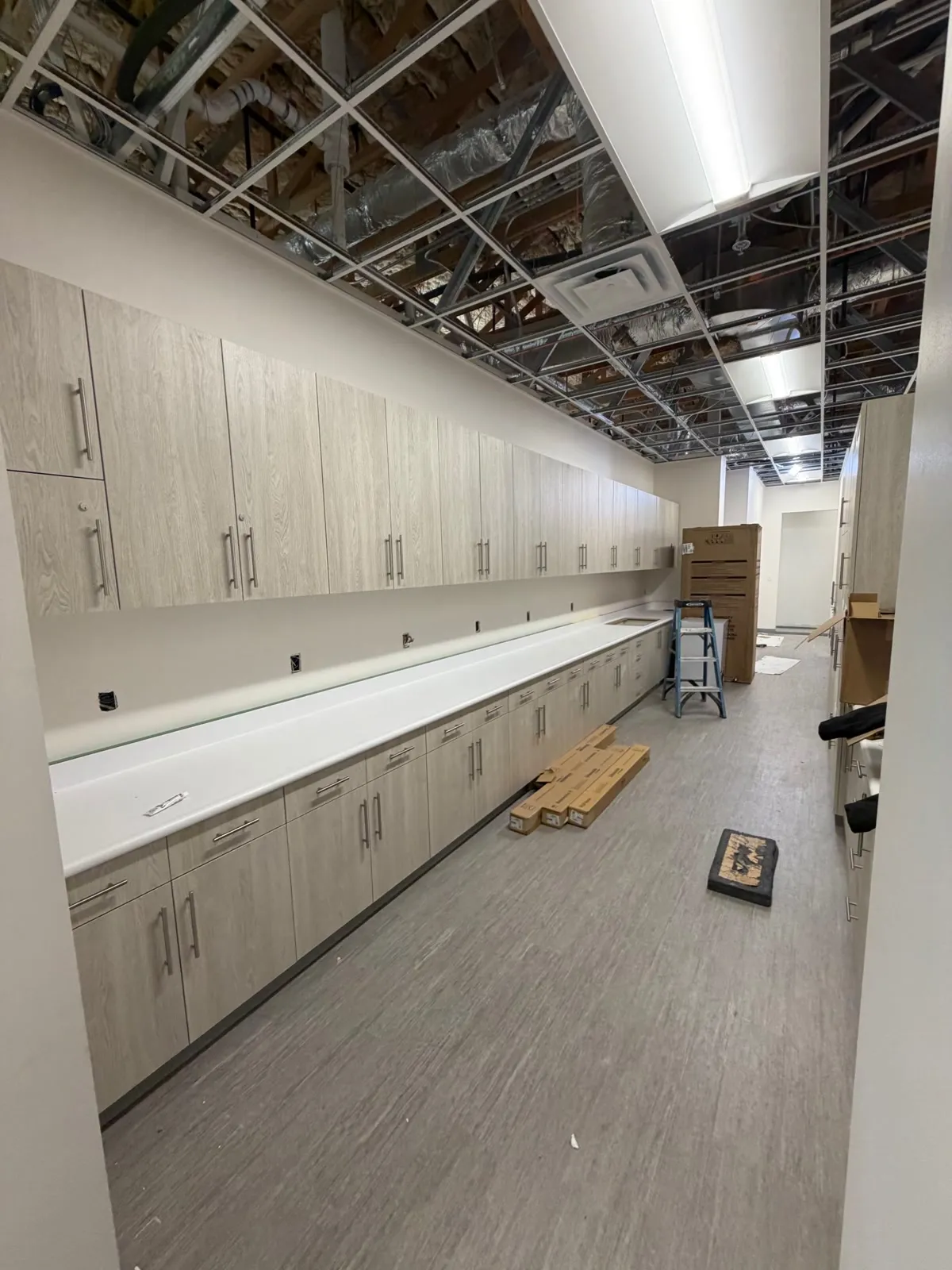 Long run of laminate base and upper cabinets with a continuous white countertop down a corridor