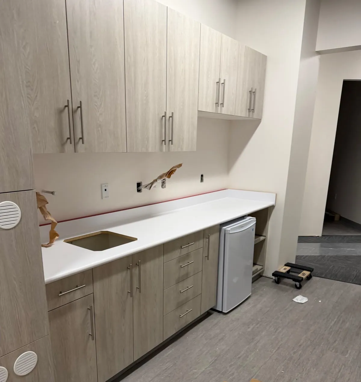 Laminate base cabinets with a drawer bank and an undermount sink in a white countertop, with upper cabinets above