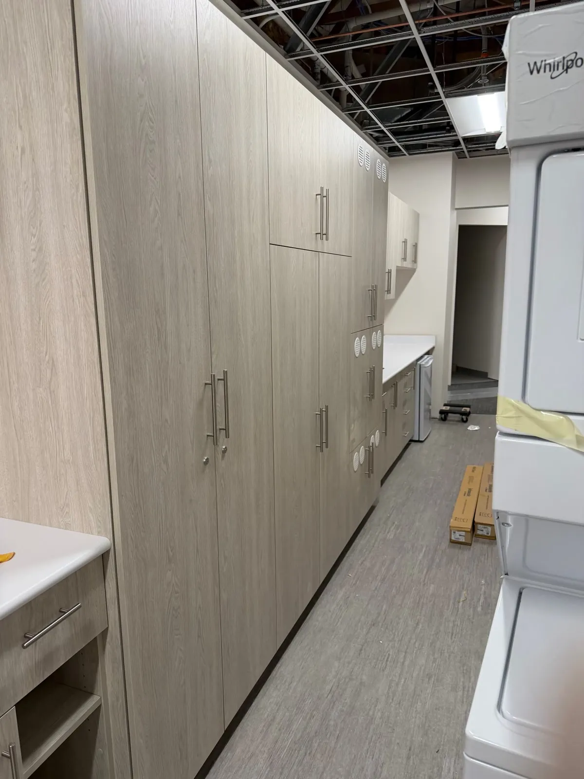 Run of full-height laminate storage cabinets with long bar pulls along a corridor
