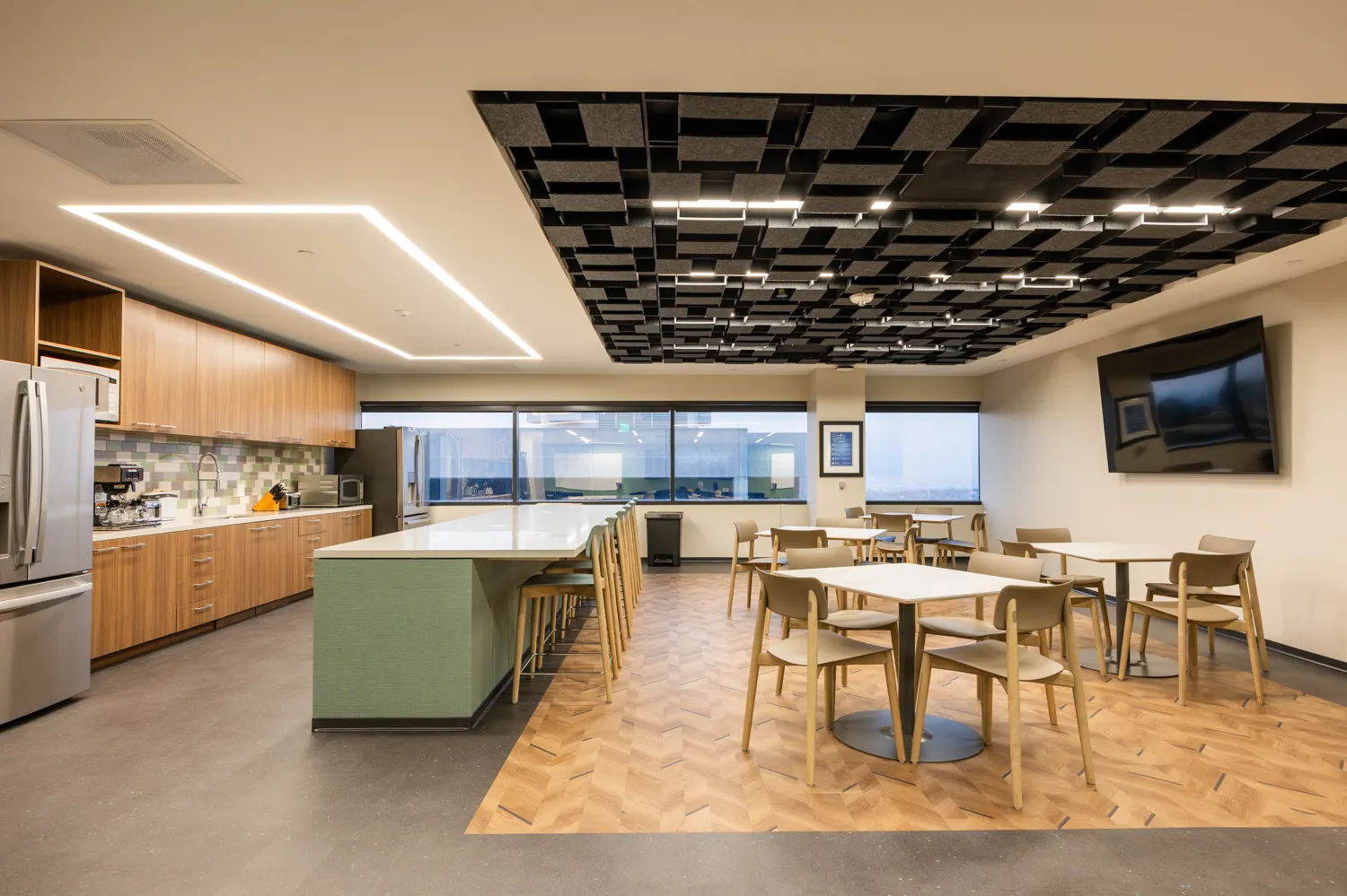 Wood-grain pantry wall cabinets and an open shelf beside a long island in Rehrig Pacific's headquarters break room
