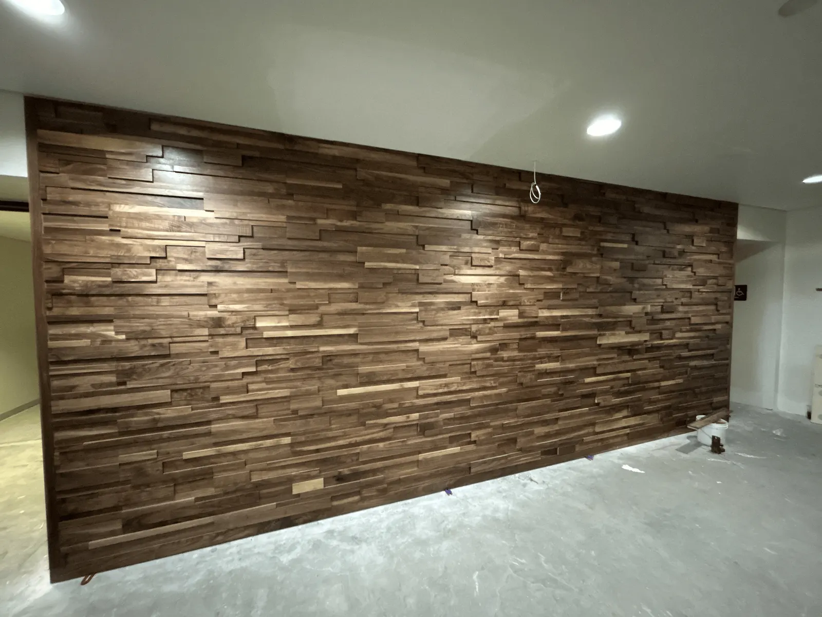 Front view of a full ledge-pattern walnut wall, its stepped solid-wood courses catching the light
