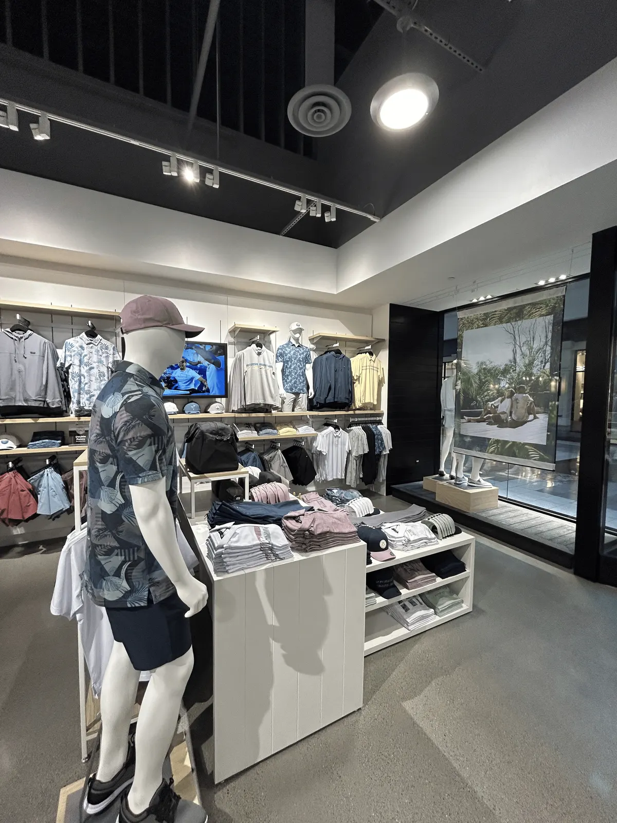White merchandise table and light wood wall shelving beside a window display platform behind the storefront glass